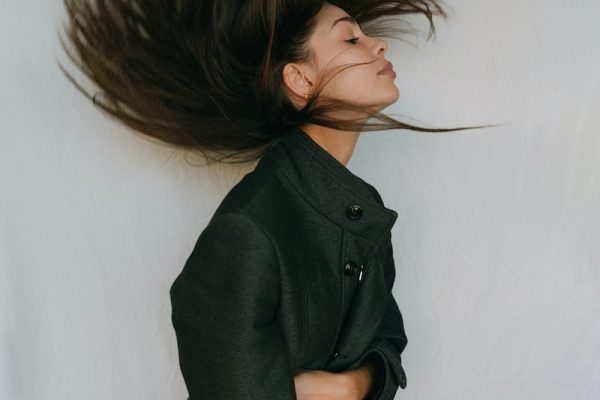 woman in black coat holding her hair